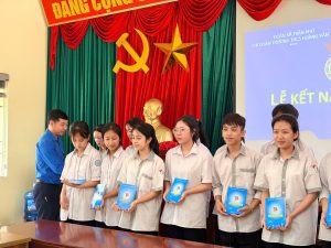 Đồng chí Dương Nguyên Giáp và đồng chí Nguyễn Thị Hiền trao huy hiệu đoàn, sổ đoàn viên cho các em học sinh